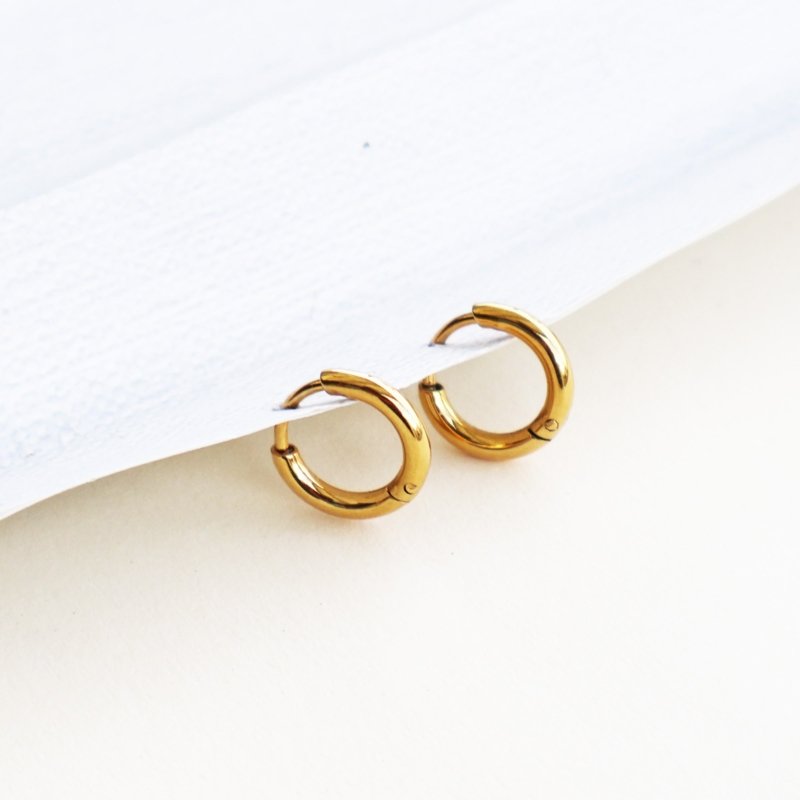 Pair of classic gold huggie earrings displayed on a white surface.