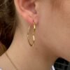 Gold hoop earring with subtle heart-shaped curve on a model.